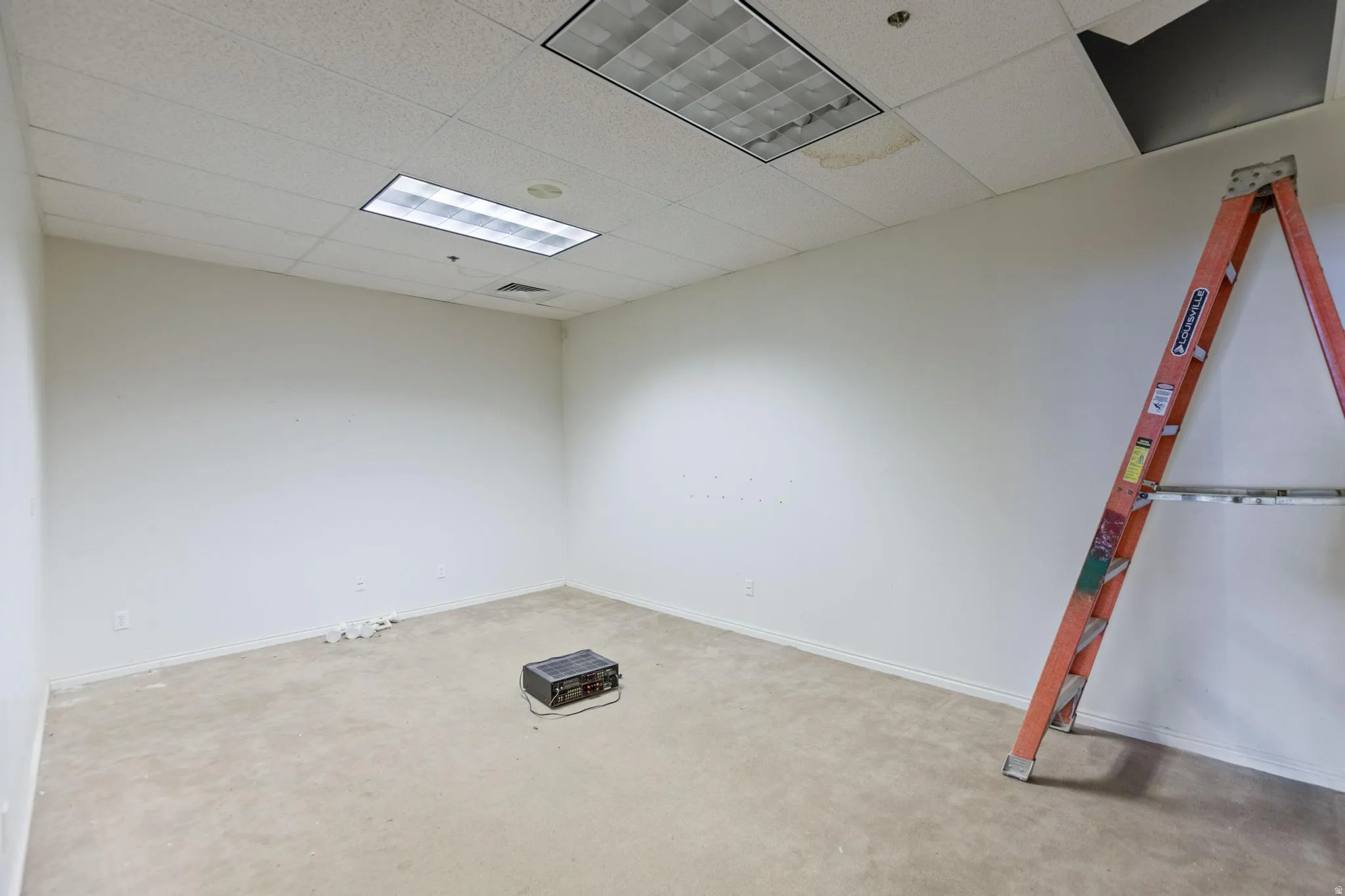 Unfurnished room with a drop ceiling and light carpet