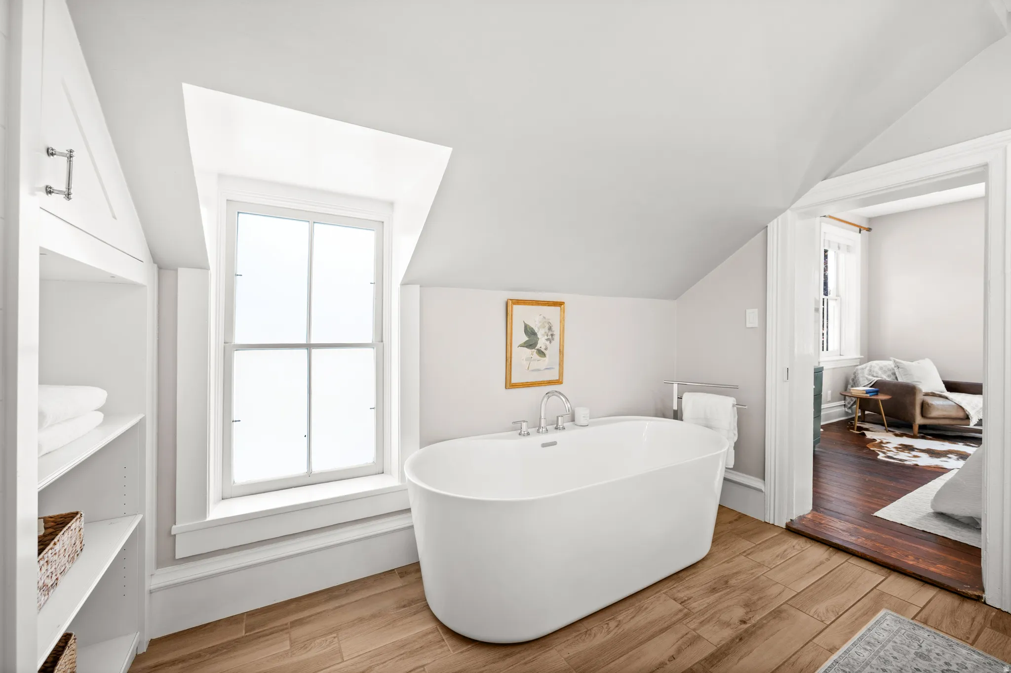 Bathroom with light wood-style floors, a soaking tub, and lofted ceiling