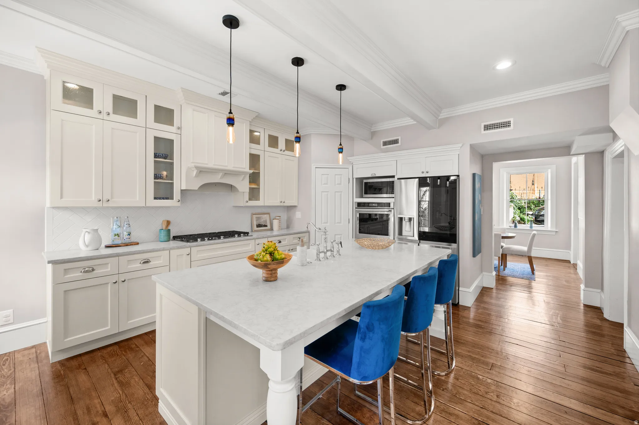 Kitchen with dark wood-type flooring, glass insert cabinets, a kitchen bar, white cabinetry, and backsplash