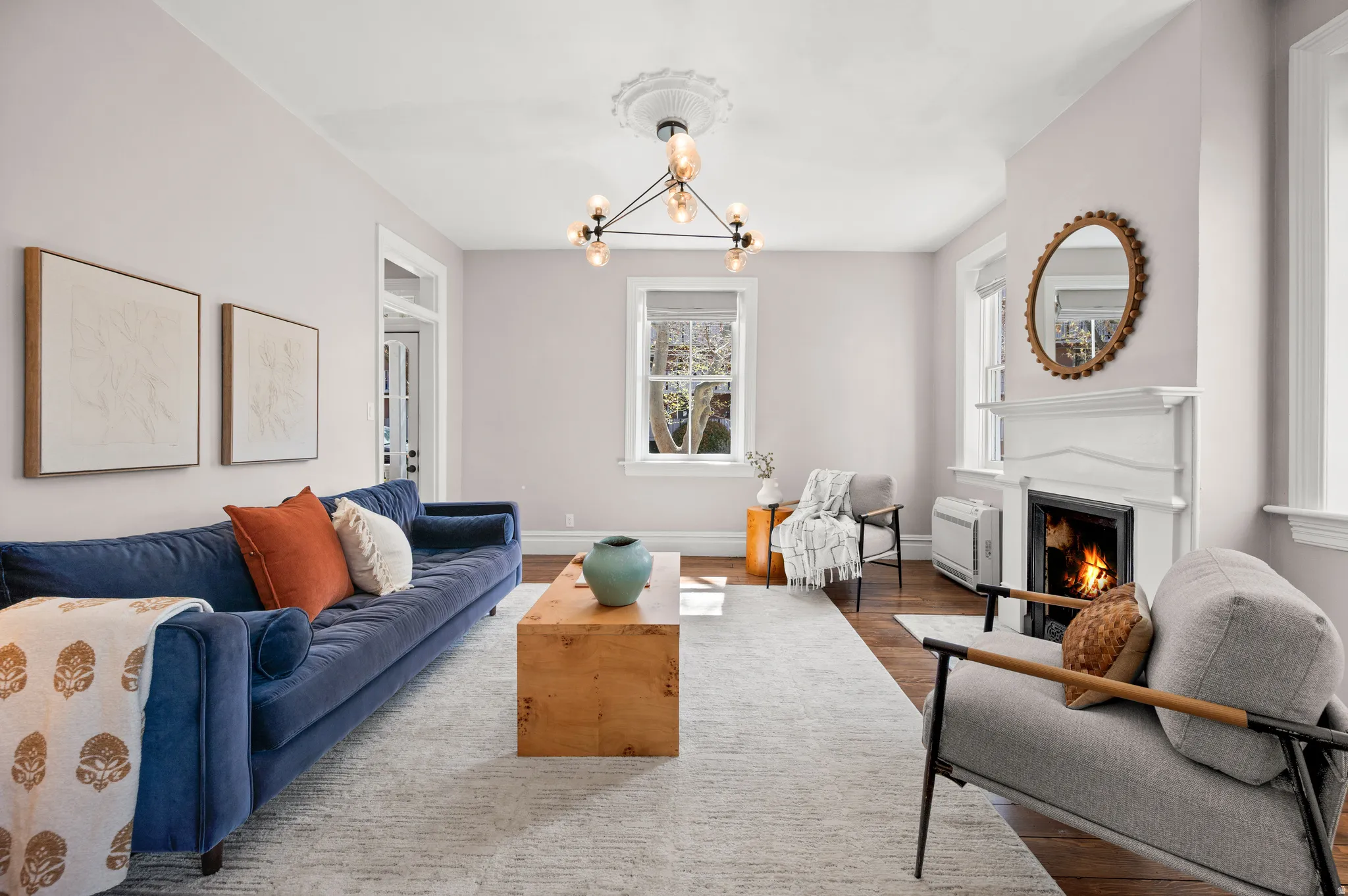 Living room featuring a lit fireplace, suspended lighting, and wood finished floors
