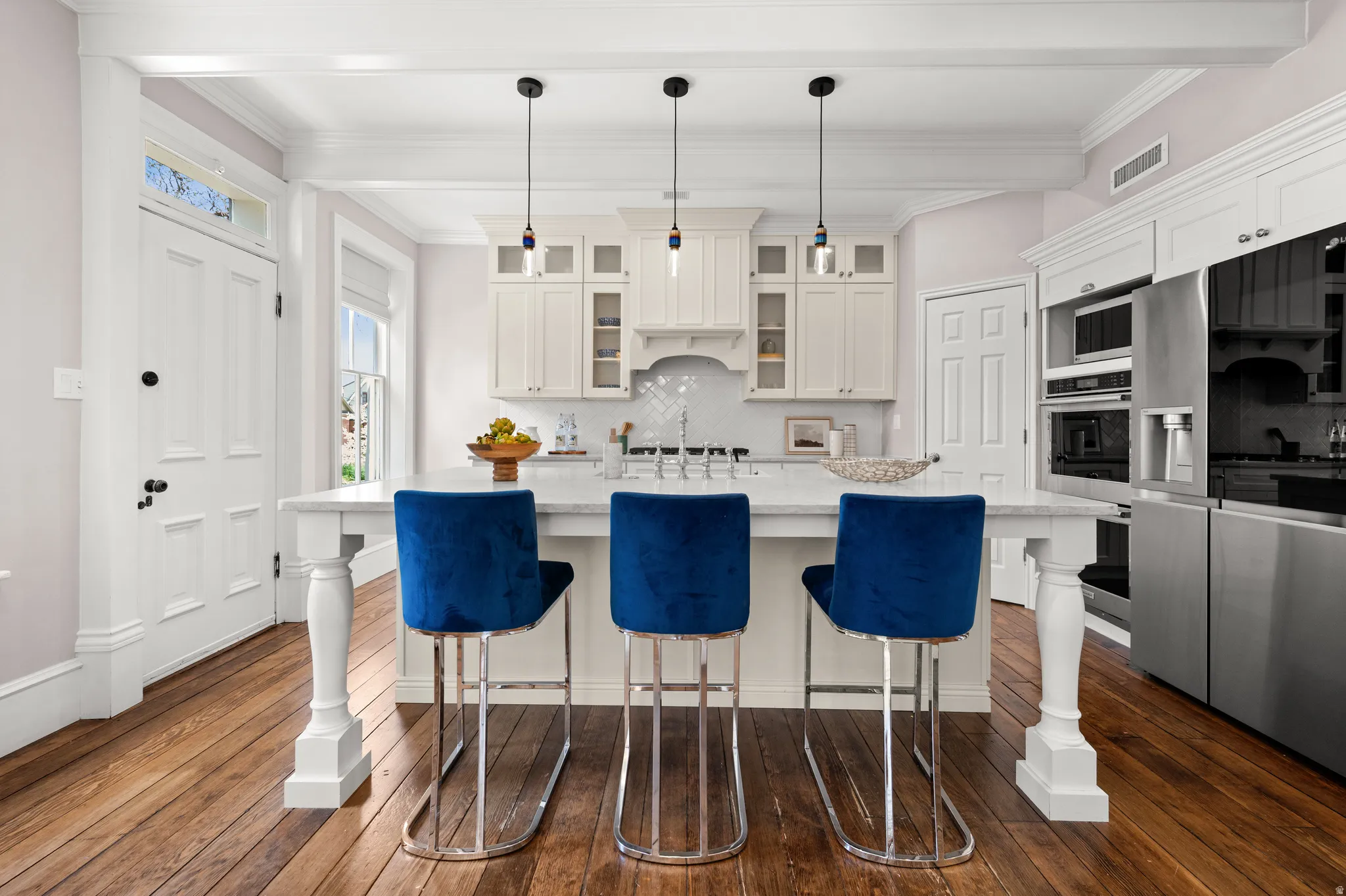 Kitchen featuring glass insert cabinets, white cabinetry, a center island with sink, backsplash, and ornamental molding