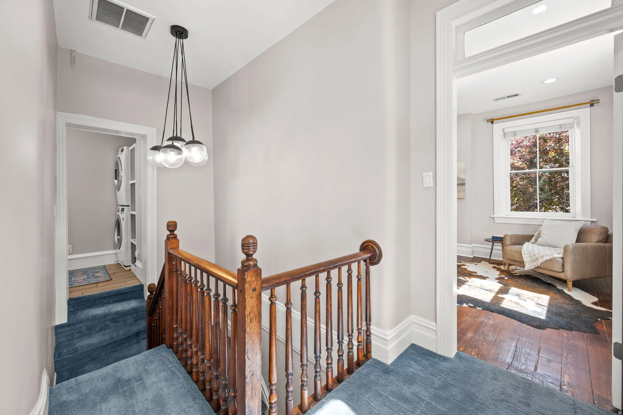 Staircase with stacked washing machine and dryer and hardwood / wood-style flooring
