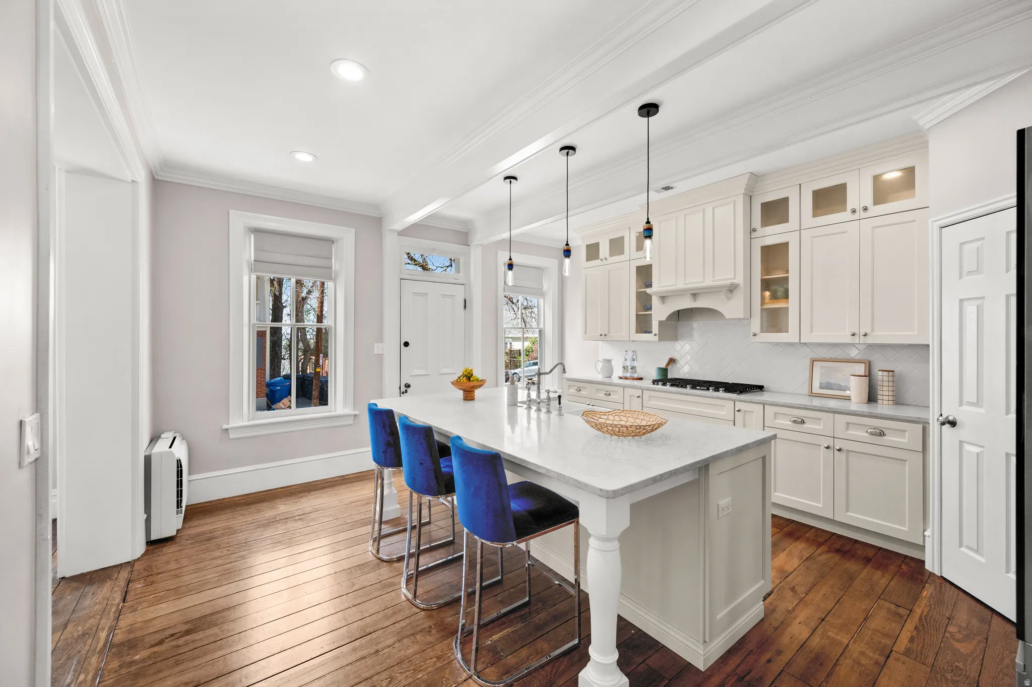 Kitchen featuring crown molding, glass fronted cabinets, dark wood-style flooring, a kitchen breakfast bar, and backsplash
