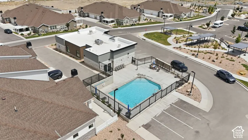 Outdoor swimming pool area featuring a perimeter fence, surrounding patio, and adjacent clubhouse-style building