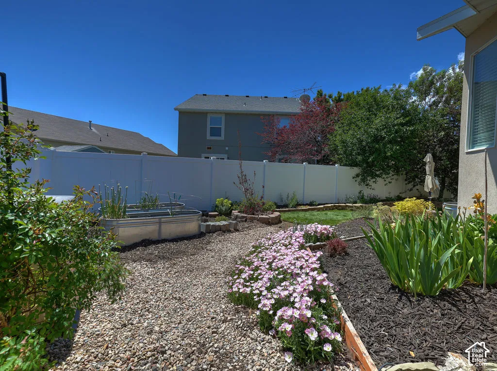 Landscaped backyard featuring a gravel pathway, raised garden beds, and vibrant floral plantings