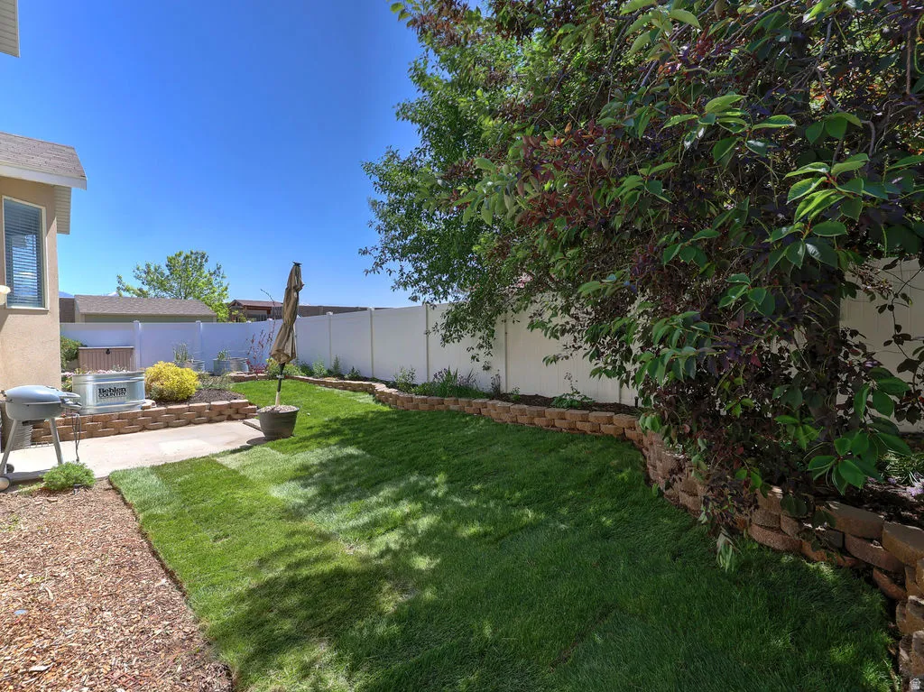 Private backyard space featuring a concrete patio, a retaining wall with planting areas, and a lawn section