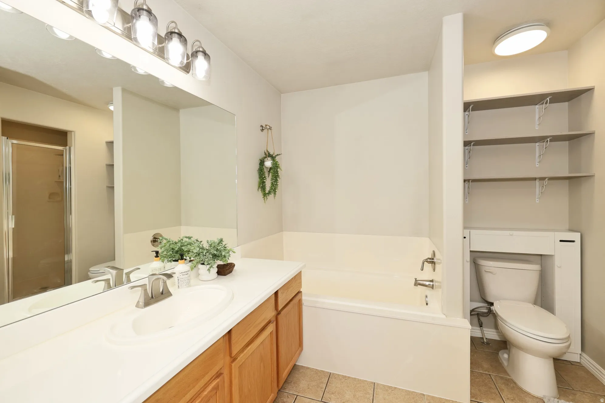 Full bathroom featuring vanity, a bath, light tile patterned flooring, and a stall shower