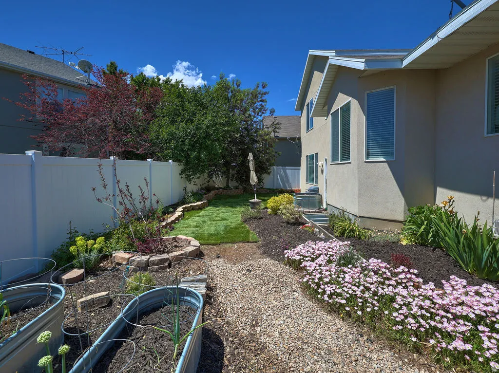 Backyard featuring a gravel path, raised garden beds, and manicured landscaping