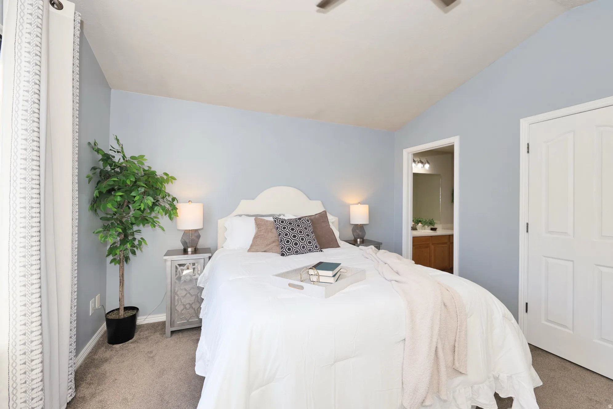 Carpeted bedroom featuring lofted ceiling, ceiling fan, and ensuite bath