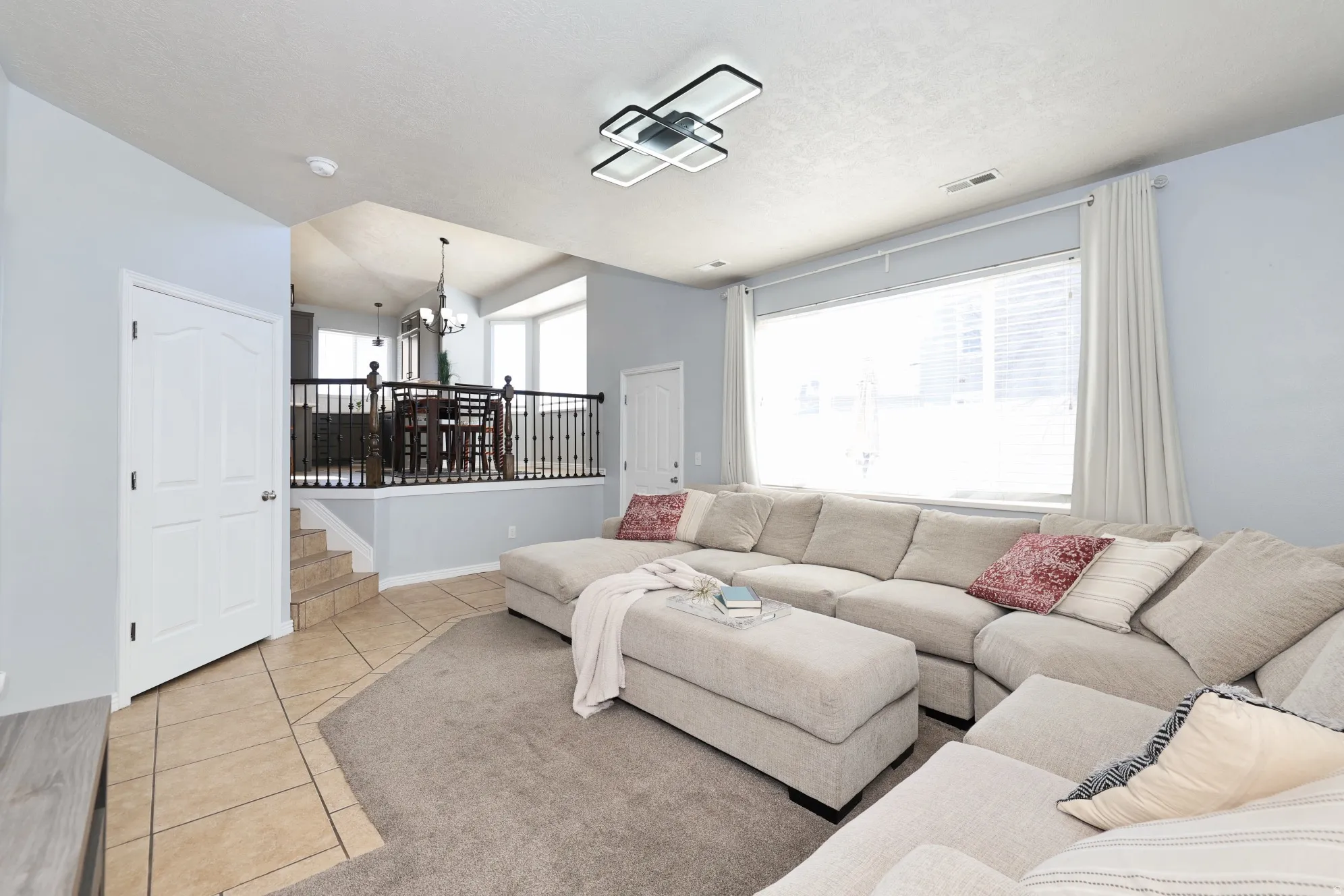 Living area with light tile patterned floors and suspended lighting