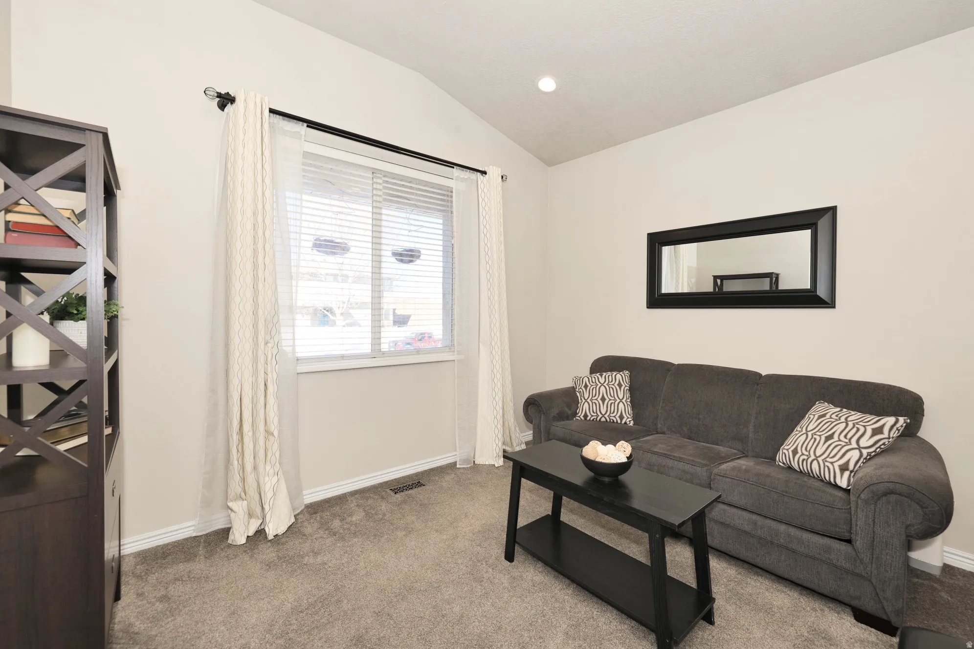 Living area with vaulted ceiling, recessed lighting, and light colored carpet