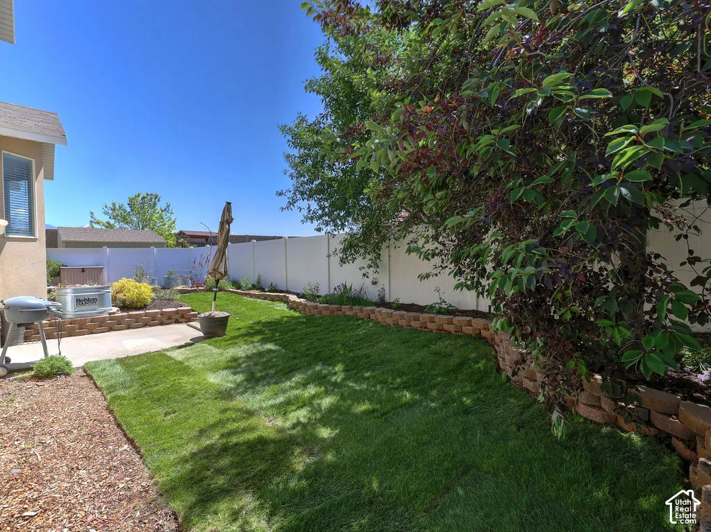 Private backyard space featuring a concrete patio, a retaining wall with planting areas, and a lawn section