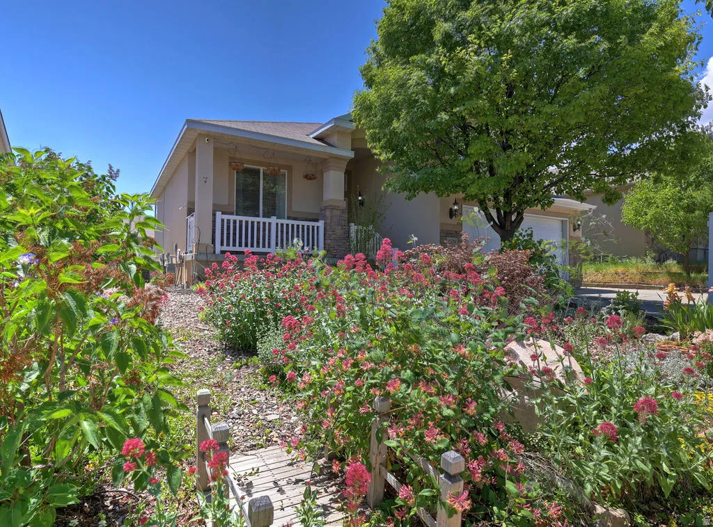 Manicured front yard with extensive mature landscaping and blooming red flowers