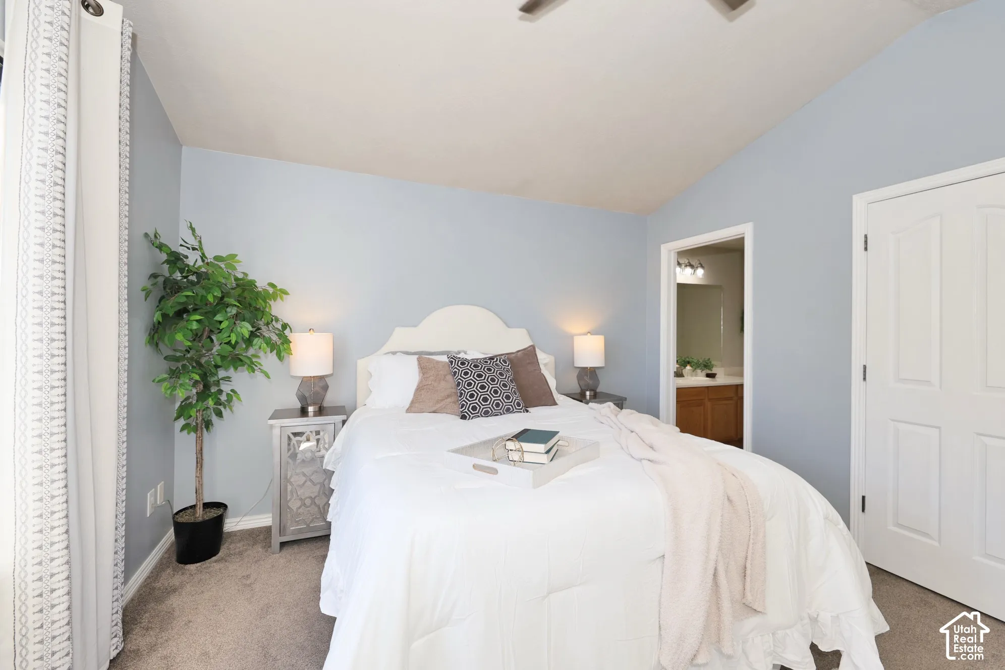 Carpeted bedroom featuring lofted ceiling, ceiling fan, and ensuite bath