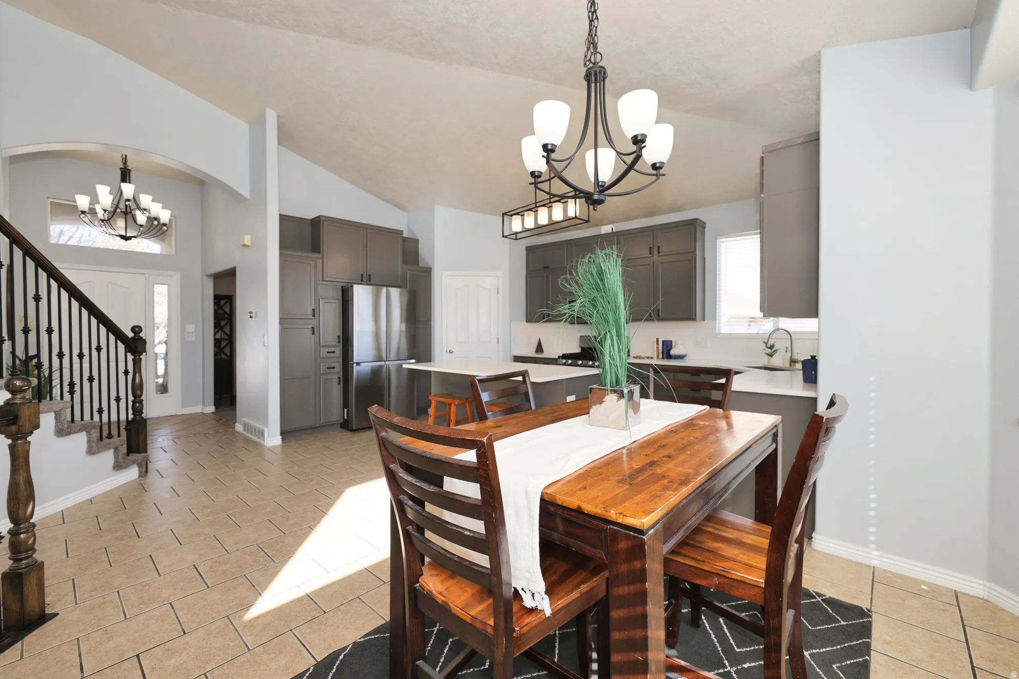 Dining space with hanging lights, vaulted ceiling, light tile patterned flooring, and arched walkways