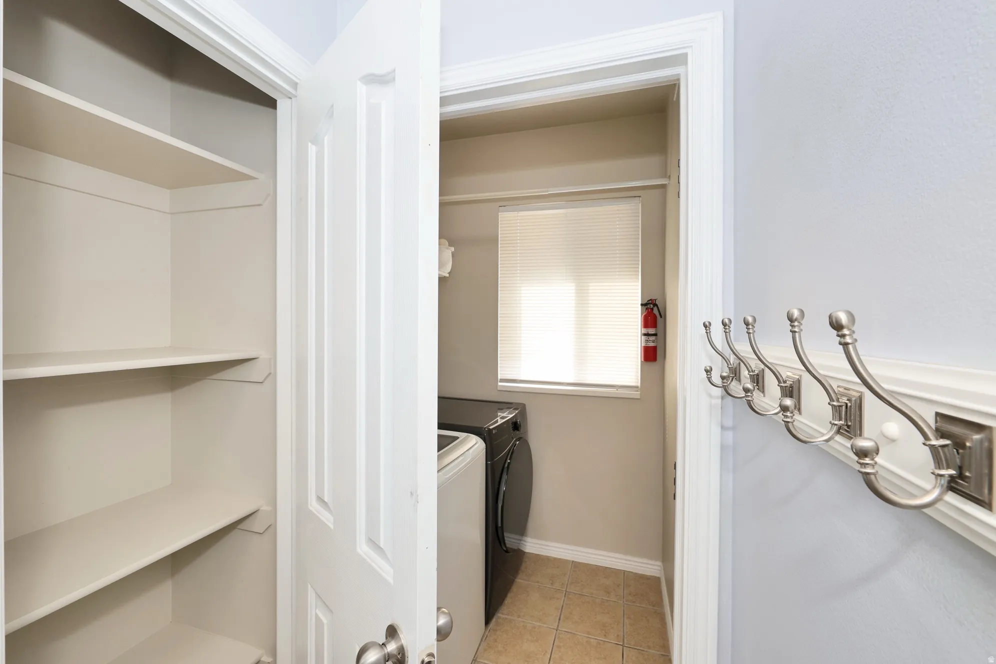 Laundry room with light tile patterned floors and washer and clothes dryer