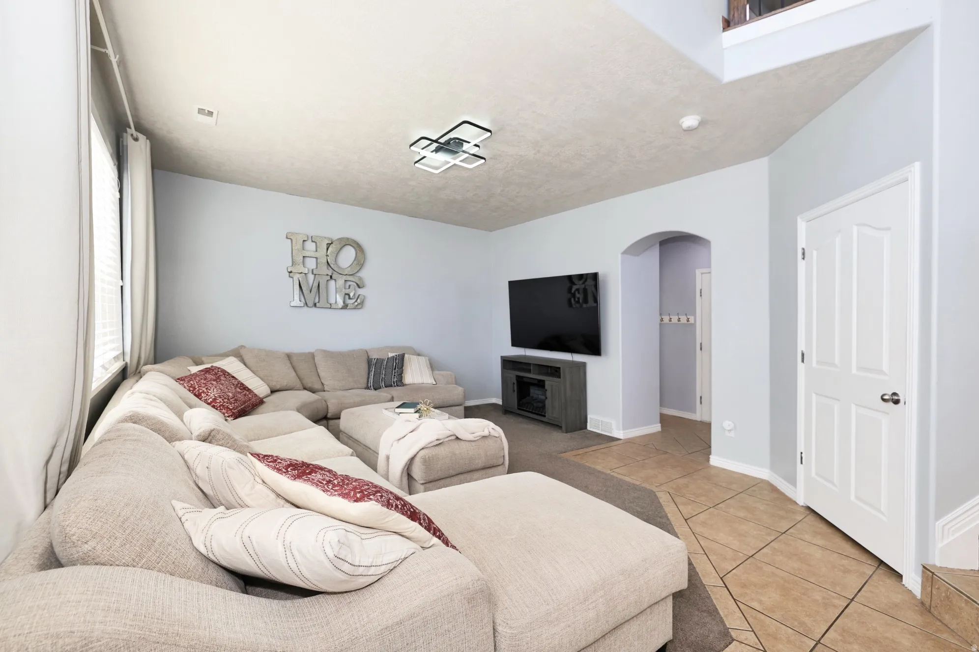 Living room with arched walkways and light tile patterned flooring