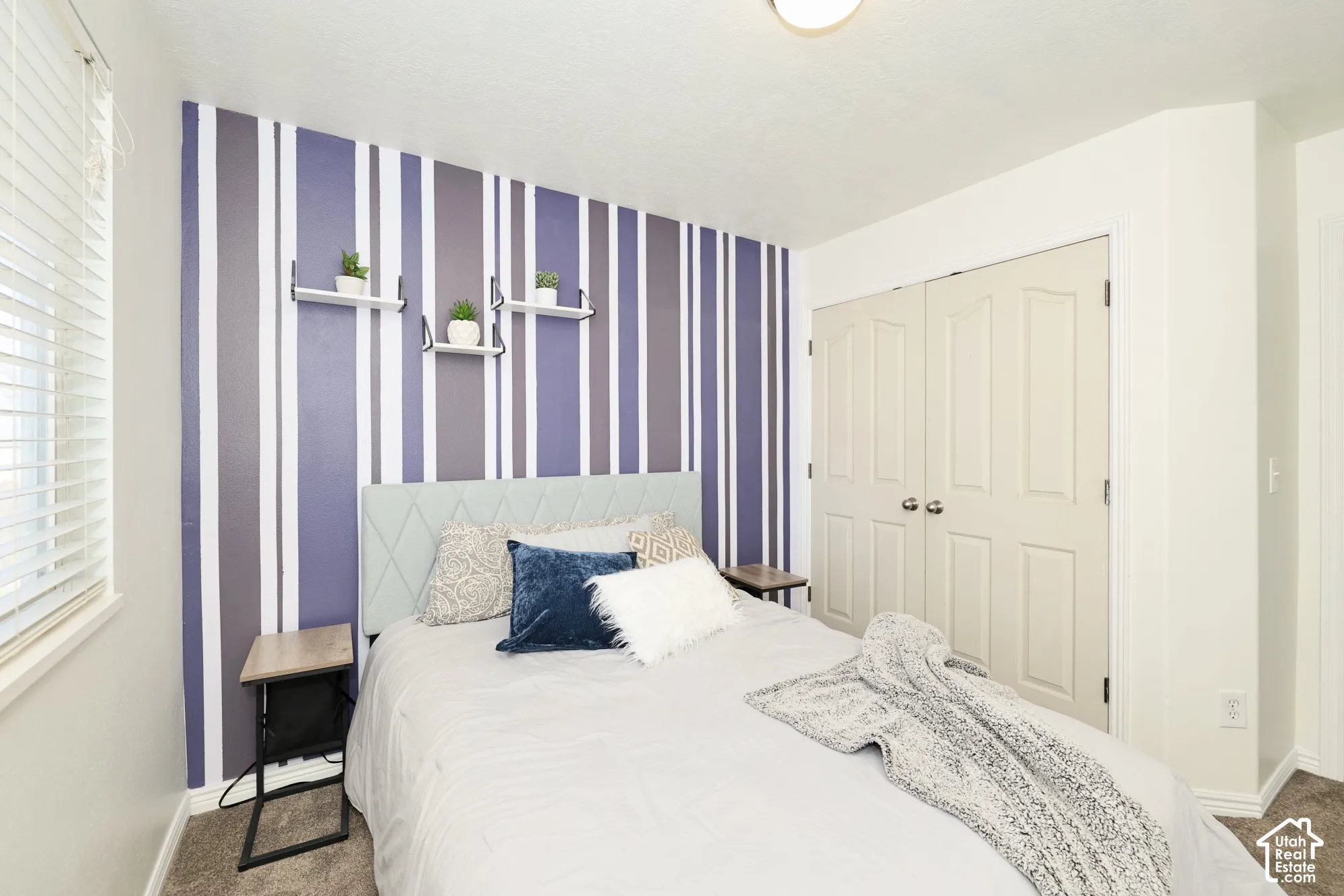Carpeted bedroom featuring wallpapered walls, a closet, and an accent wall