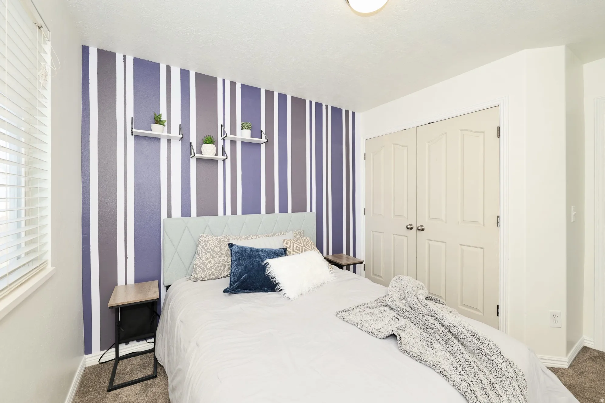 Carpeted bedroom featuring wallpapered walls, a closet, and an accent wall
