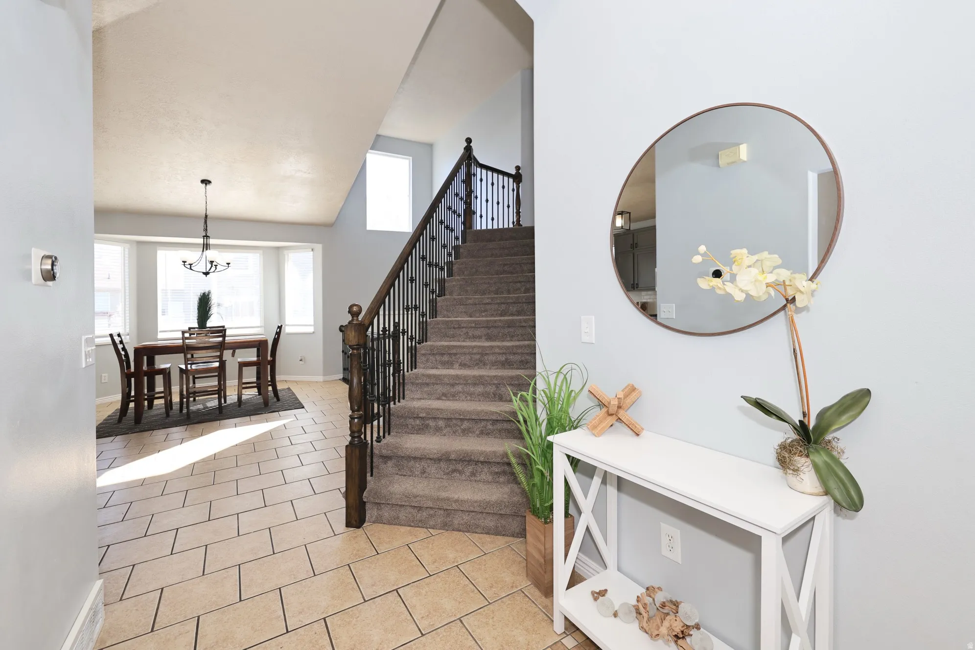 Stairway with tile patterned floors, a high ceiling, and hanging lights