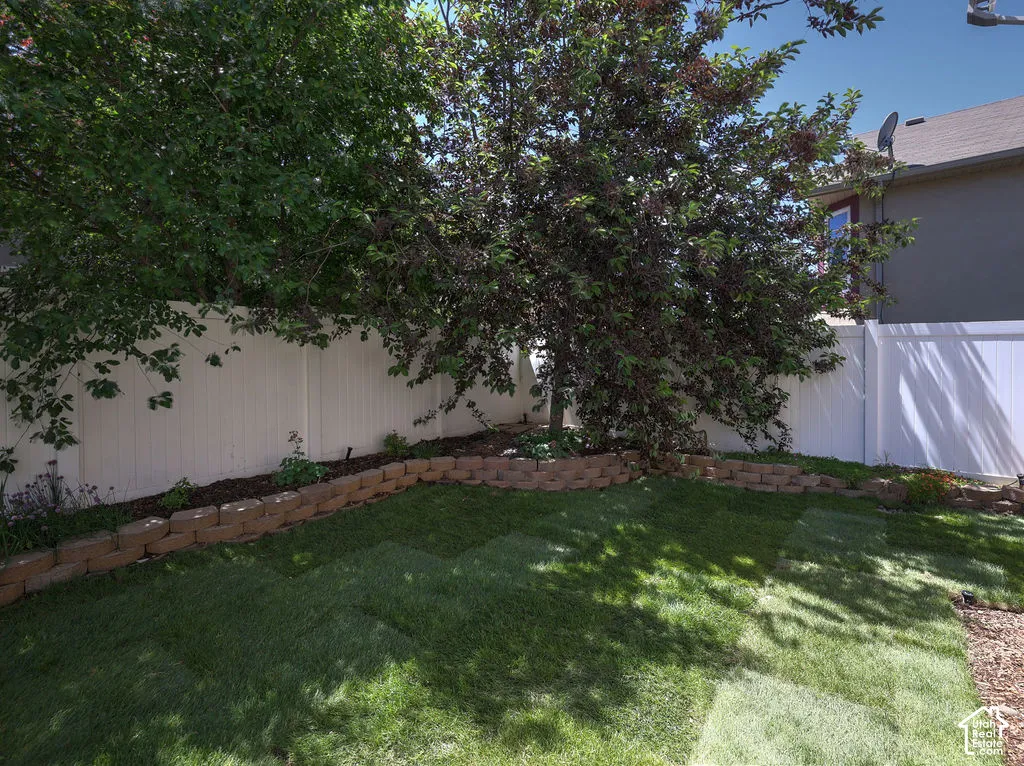 Expansive backyard featuring a manicured lawn, established trees, and a white privacy fence