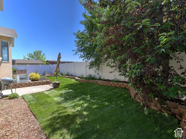 Private backyard space featuring a concrete patio, a retaining wall with planting areas, and a lawn section