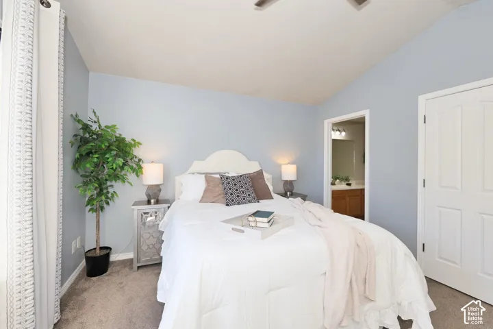 Carpeted bedroom featuring lofted ceiling, ceiling fan, and ensuite bath