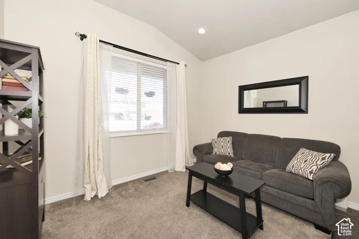 Living area with vaulted ceiling, recessed lighting, and light colored carpet
