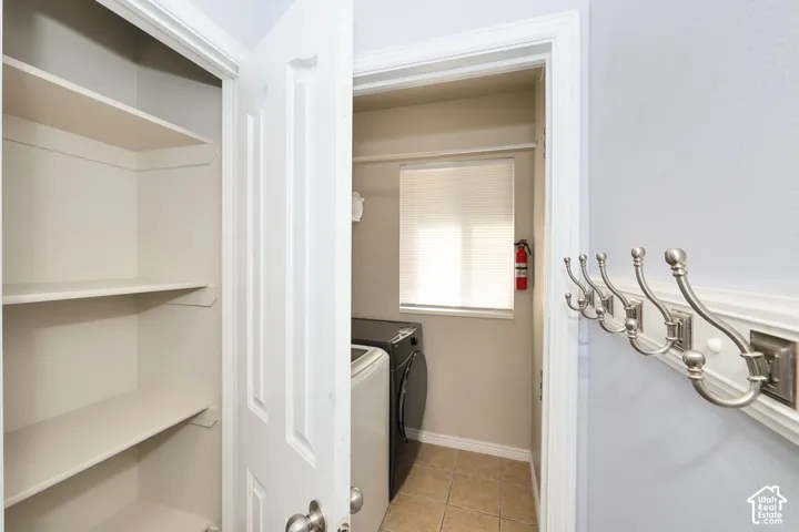 Laundry room with light tile patterned floors and washer and clothes dryer
