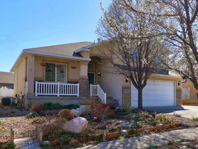 View of front of house with covered porch, driveway, stucco siding, stone siding, and a garage