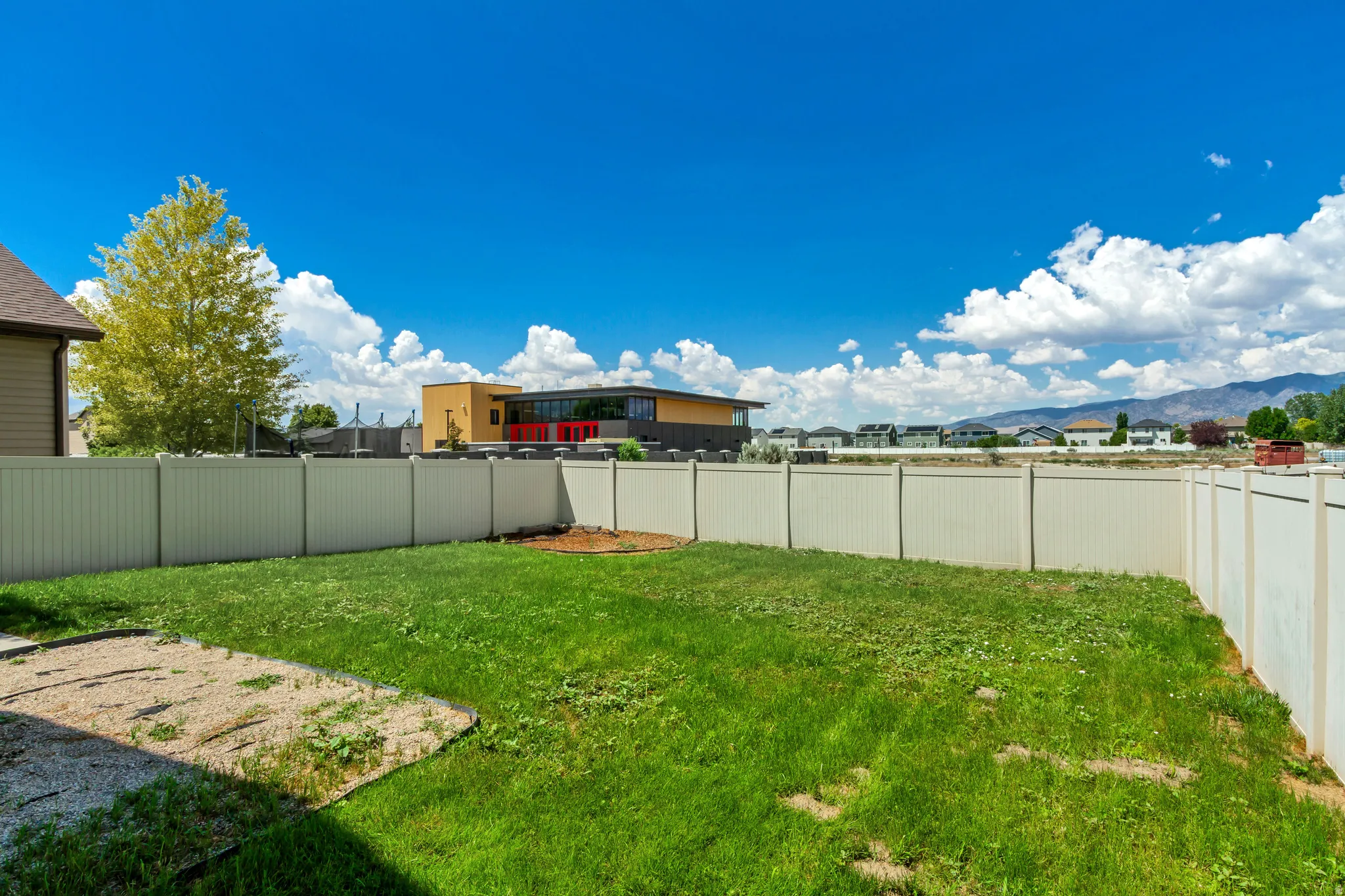Expansive backyard featuring a green lawn and a light-colored vinyl privacy fence