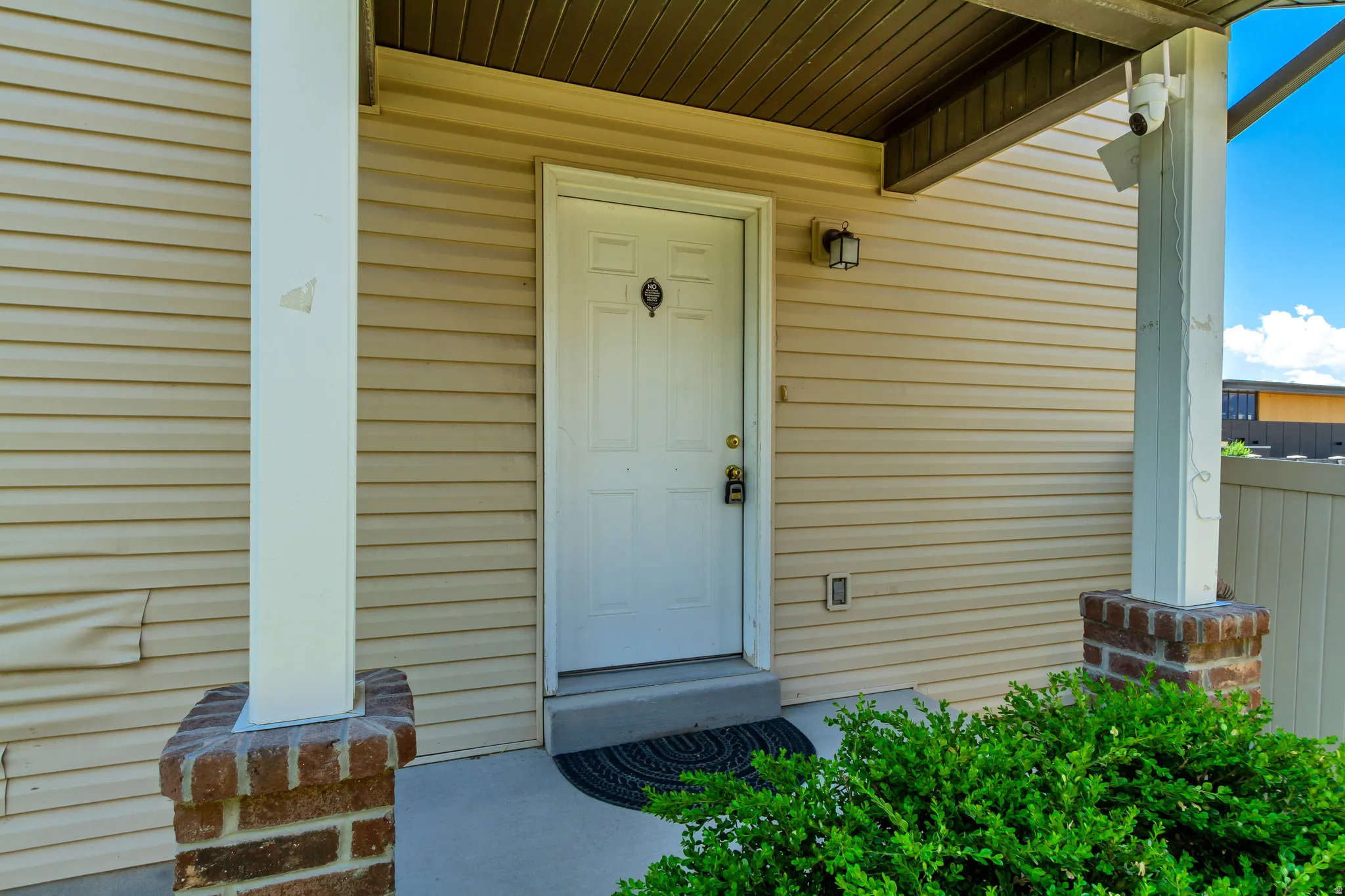 Covered entry featuring a white panel door with hardware, exterior wall lighting, and beige horizontal siding