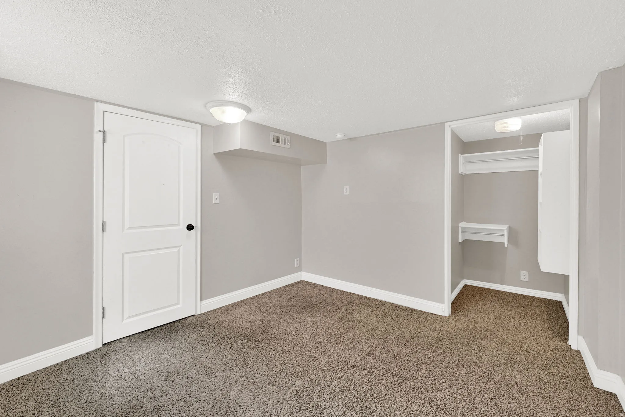 Finished below grade area with a textured ceiling and dark colored carpet