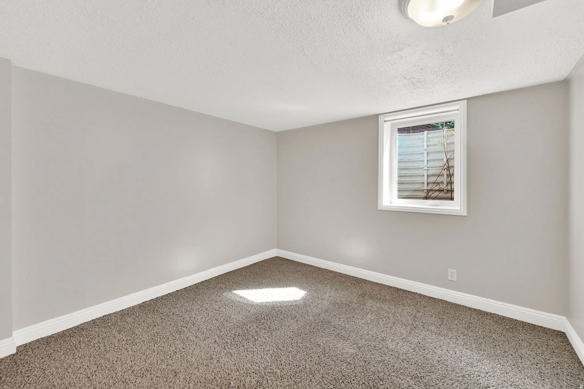 Unfurnished room with light carpet and a textured ceiling