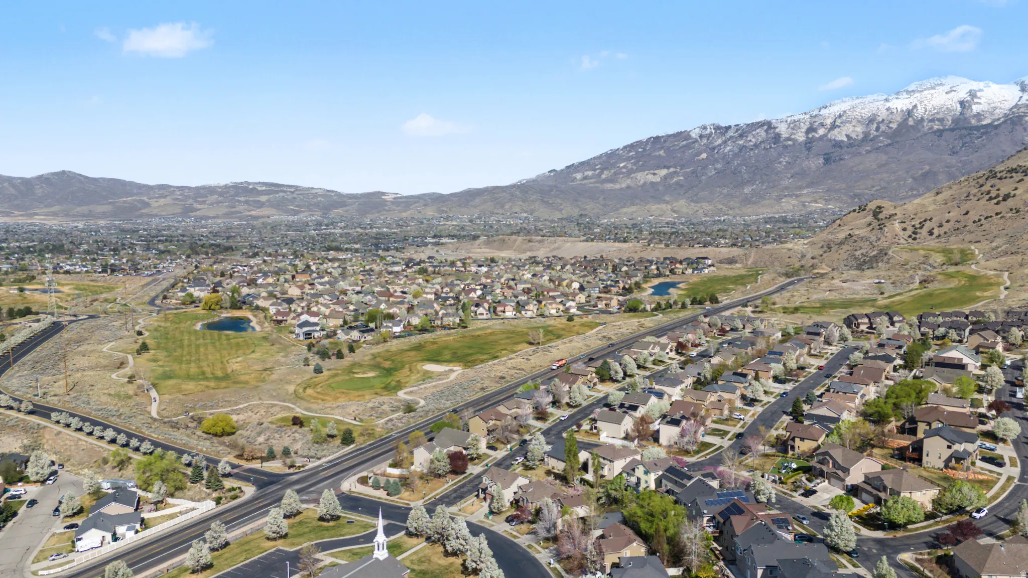 Aerial perspective of suburban area featuring a mountain backdrop and a golf course