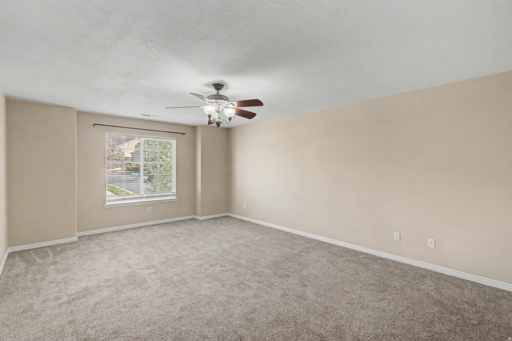 Carpeted empty room featuring ceiling fan and a textured ceiling