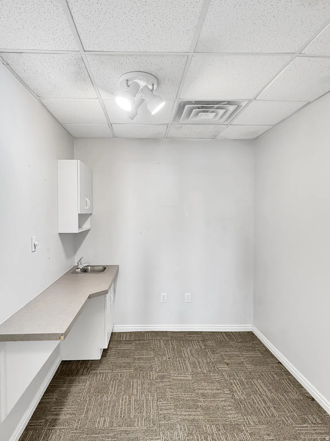 Unfurnished office featuring a paneled ceiling and dark colored carpet