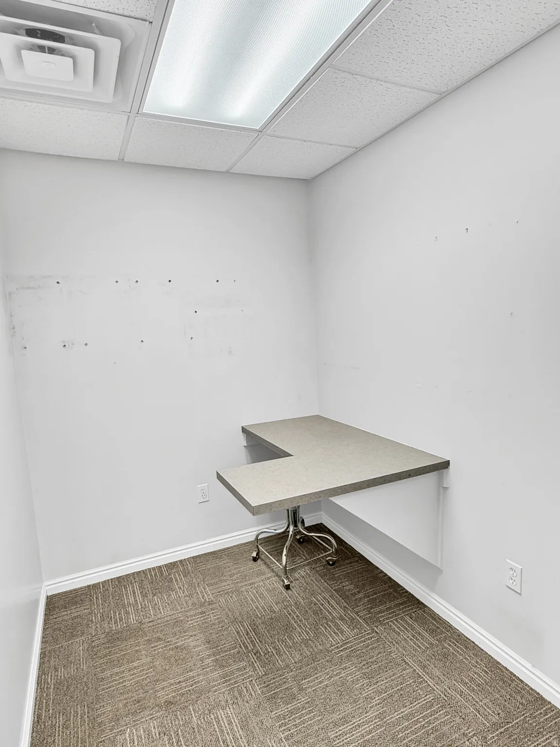 Unfurnished office with dark carpet and a drop ceiling