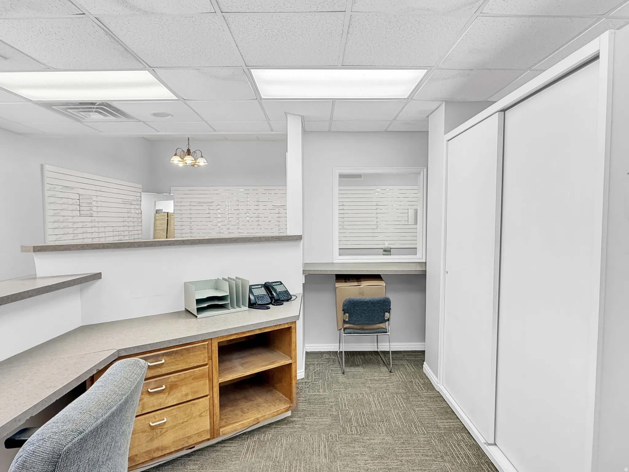Home office featuring suspended lighting, built in desk, and a drop ceiling