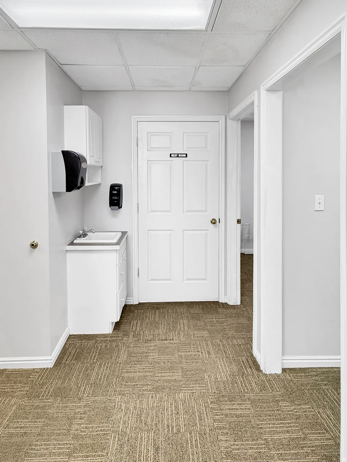 Hallway with a drop ceiling and light carpet