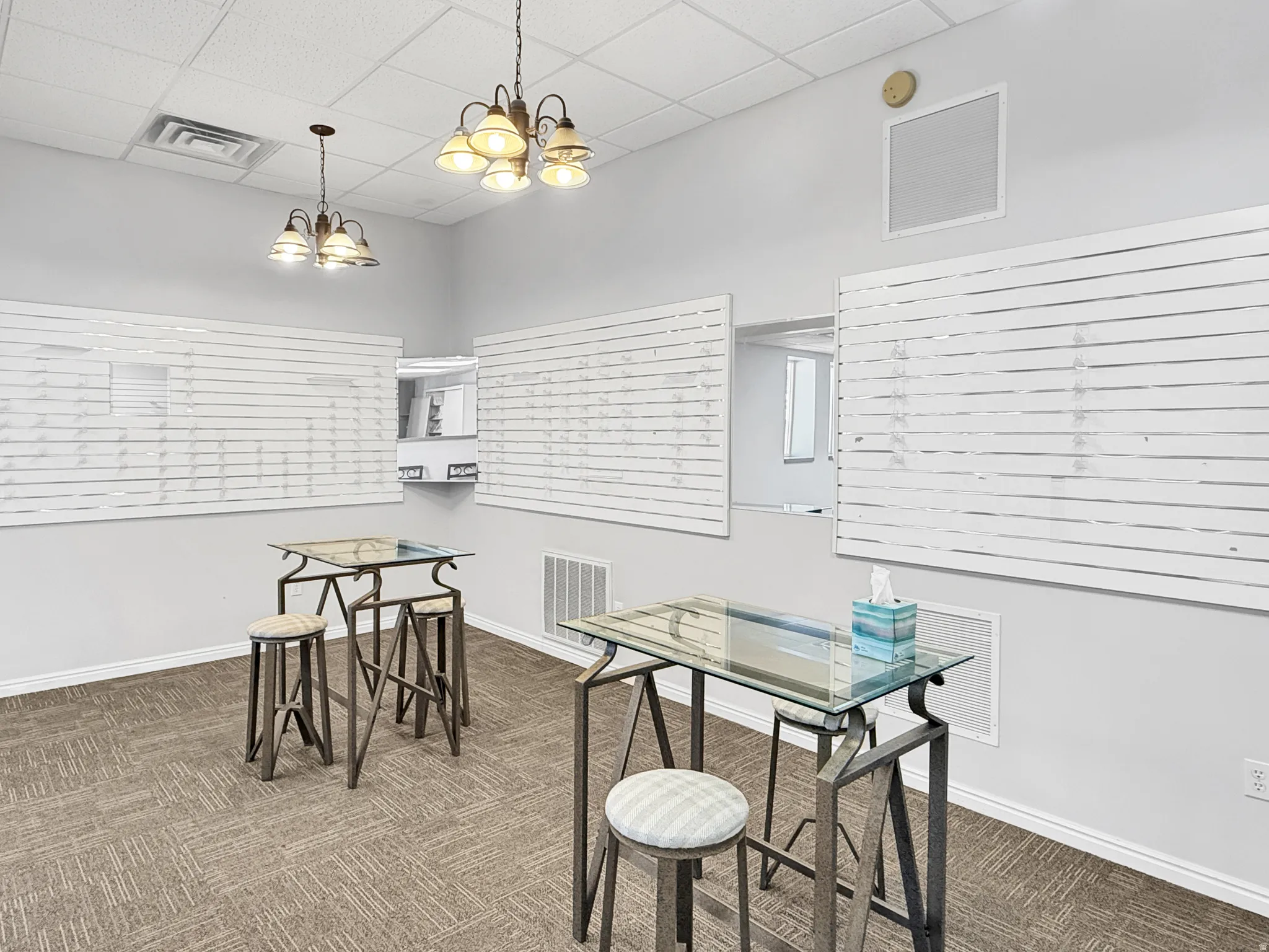 Dining area featuring dark colored carpet, a paneled ceiling, and a chandelier
