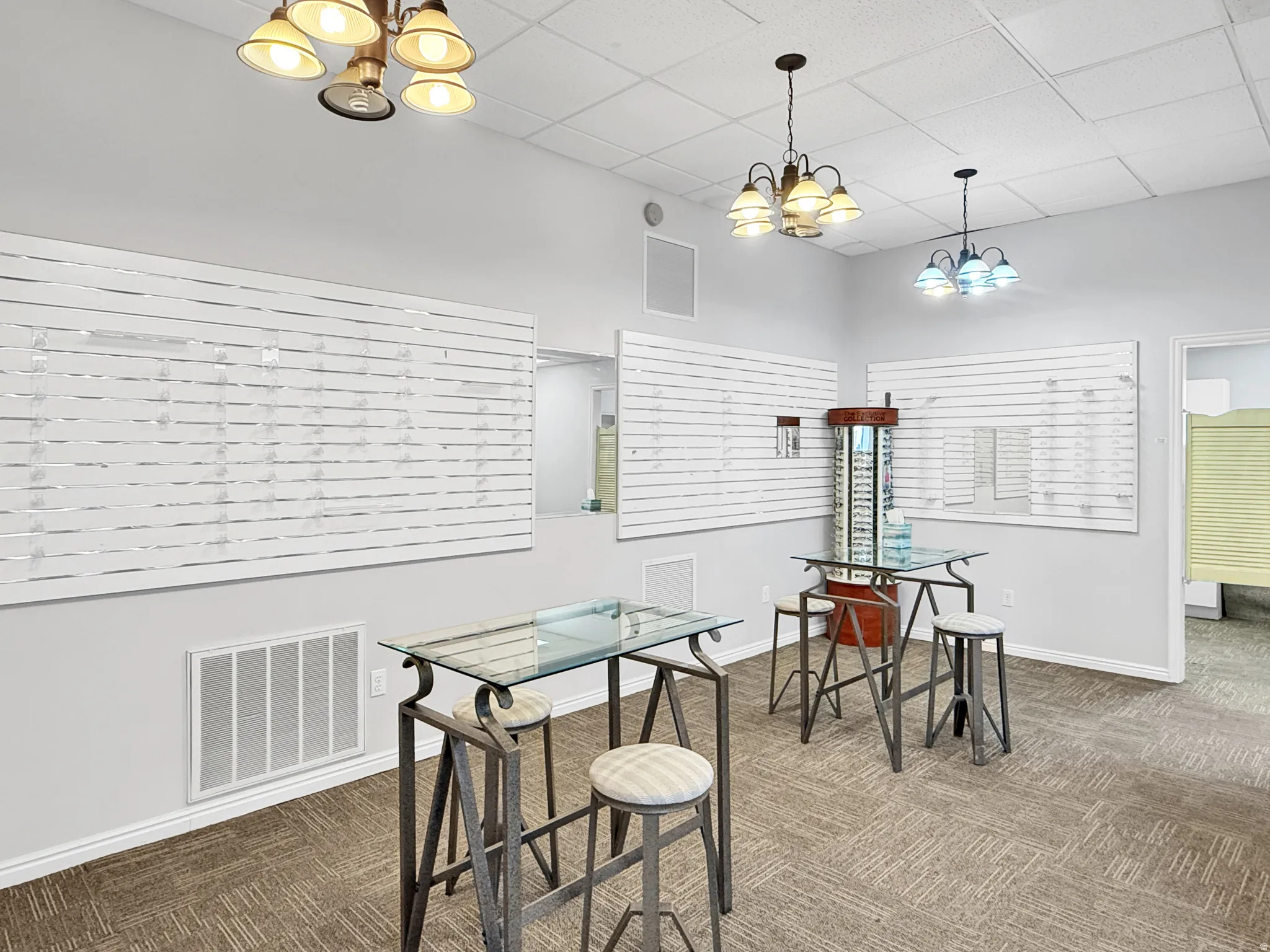 Dining space with suspended lighting, dark carpet, and a drop ceiling
