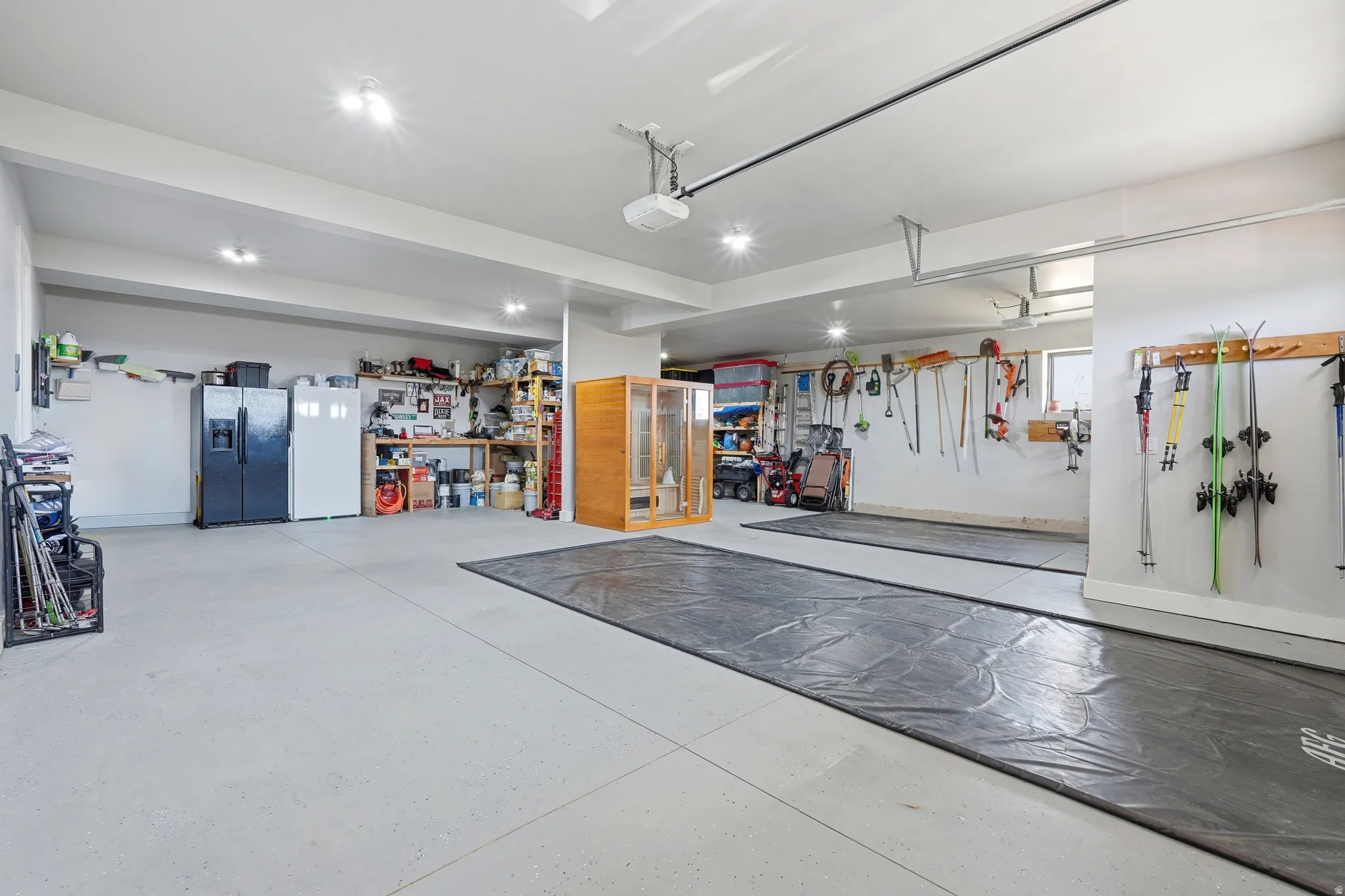 Garage with stainless steel fridge with ice dispenser, freestanding refrigerator, and a garage door opener