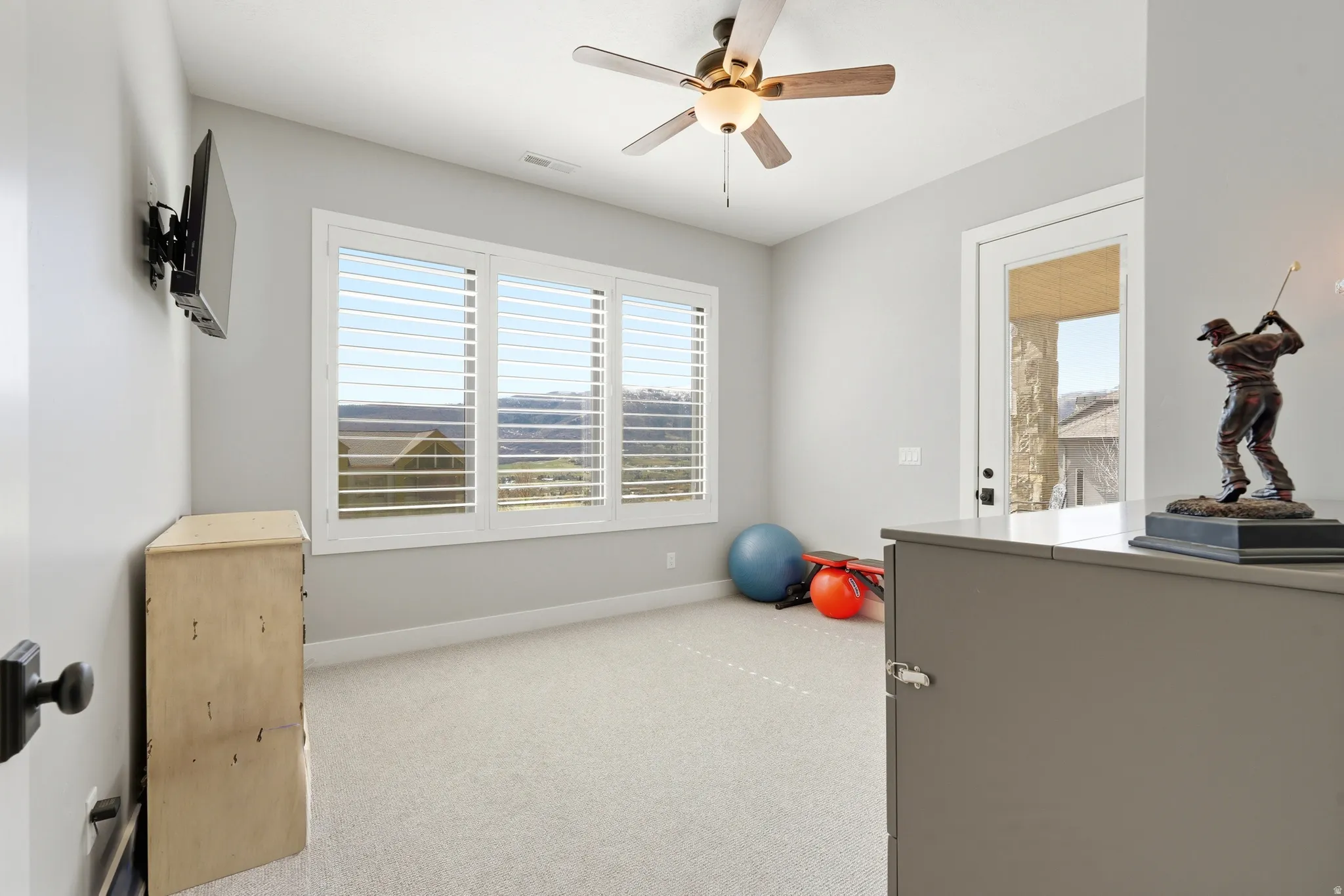 Exercise room featuring a ceiling fan, light carpet, and healthy amount of natural light