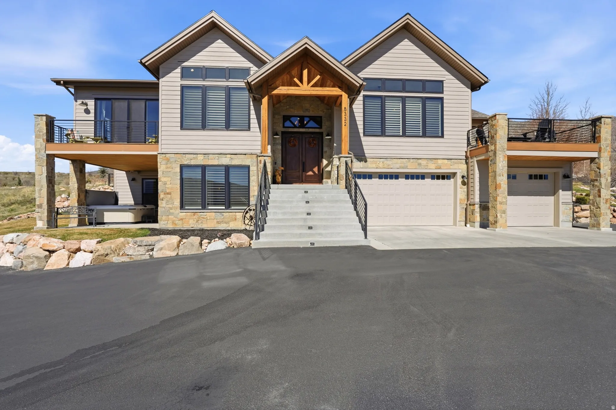 View of front of property with stone siding, driveway, and a garage