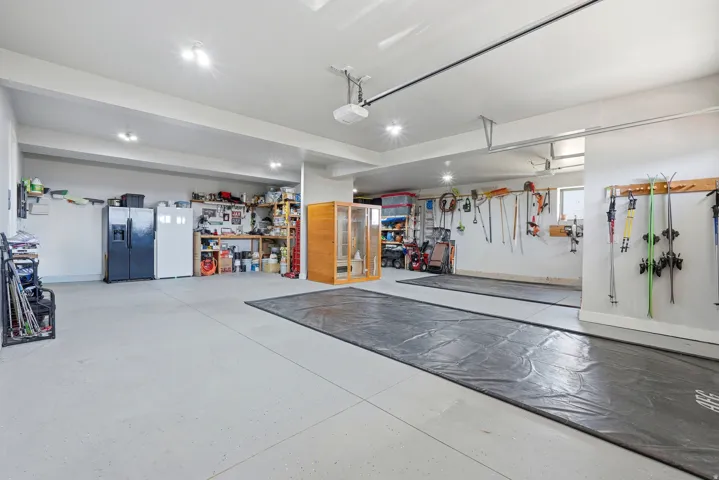Garage with stainless steel fridge with ice dispenser, freestanding refrigerator, and a garage door opener