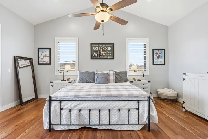 Bedroom with hardwood / wood-style flooring, multiple windows, ceiling fan, and lofted ceiling
