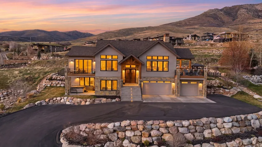 View of front of property featuring stone siding, a mountain view, a garage, driveway, and a chimney