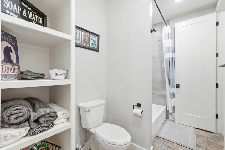 Full bathroom featuring toilet and shower / bathtub combination with curtain
