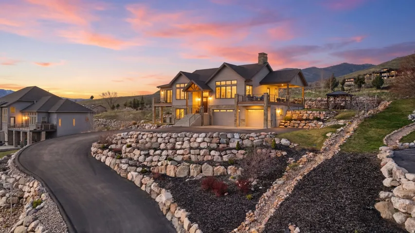 View of front of home featuring a balcony, a chimney, a garage, driveway, and a mountain view